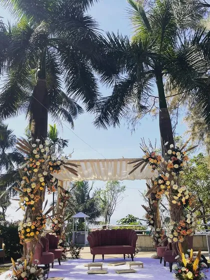 A beautiful mandap setup for a daytime ceremony with a view of the sea. The design uses pampas grass and dried florals for a bohemian-chic vibe, perfectly complementing the natural surroundings.