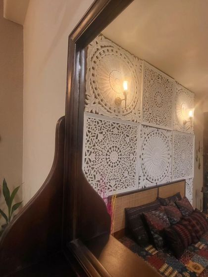 This mirror reflects a unique headboard made of intricately carved white panels, showcasing how reflective surfaces can highlight other design details.