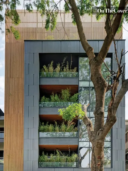 A modern apartment building where the balconies are designed as deep planters, allowing residents to have their own gardens. The integration of wood and slate-colored panels complements the natural greenery.