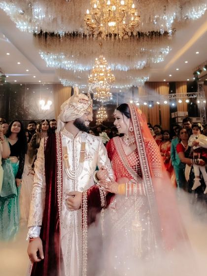 The couple's grand entrance into the banquet hall, walking through a cloud of smoke under magnificent chandeliers.