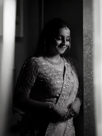 A soft and intimate black and white portrait, shot through a doorway. This framing creates a sense of looking in on a private, happy moment.