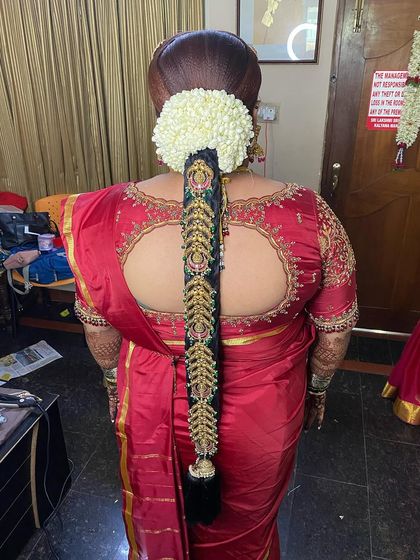 This is a classic Muhurtham braid, complete with a jasmine gajra and a full set of temple jewellery. The neatness of the braid and the richness of the accessories create a truly timeless bridal look.