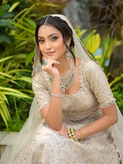 A full-length view of this modern bridal look. The makeup is kept soft and elegant to balance the heavily embellished lehenga and statement diamond and emerald jewelry.