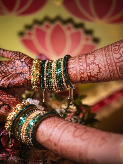 A beautiful shot of the bride's hands during a wedding ritual, with the dark mehendi stain and green bangles creating a stunning contrast.