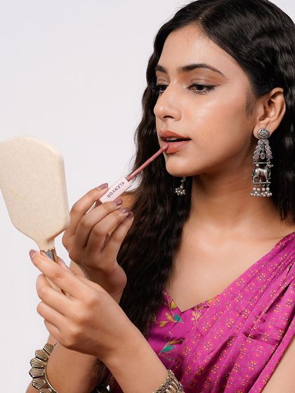 A product-in-use shot for a makeup brand. This close-up clearly showcases the lipstick application, the product itself, and the model's beautiful features, making it a highly effective commercial image.