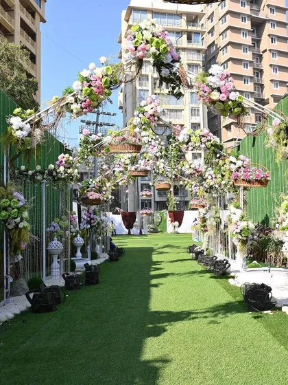 The view down the aisle of a garden wedding, with hanging floral baskets and elegant decor creating a romantic pathway for the bride.