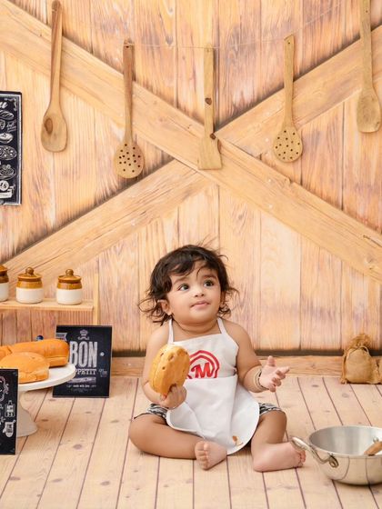 Holding a piece of bread, this little chef looks proud of his work in our charming, rustic kitchen setup.