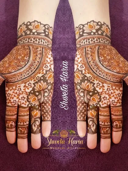 This traditional design is filled with delicate details. It features a large central mandala with lotus and elephant motifs woven into the pattern on the fingers and wrist.