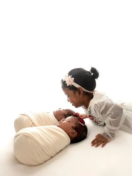 A big sister looking so lovingly at her new twin siblings. Her gentle touch and curious expression are just priceless.