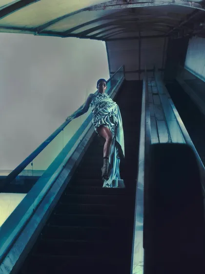 A shot from 'The Last of Them,' a project about decaying aristocracy. The model poses on an escalator, blending futuristic fashion with a mundane urban environment to create a striking contrast.