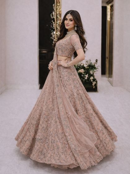 A classic and elegant pose in the dusty pink lehenga, perfect for capturing timeless photos at your special event.