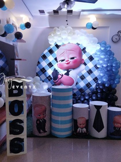 Even in a smaller space at home, I can create an impactful Boss Baby theme. This setup uses a large character inflatable, themed plinths, 'BOSS' letter blocks, and a circular checkered backdrop to transform the room.