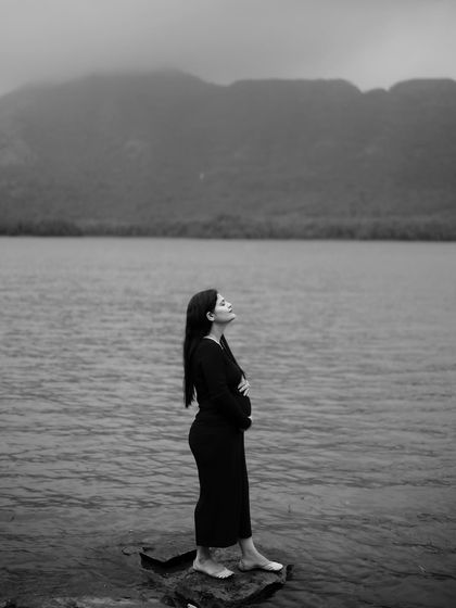 A beautiful black and white portrait of the mom-to-be looking up to the sky, standing on a rock by the water. It’s a hopeful and inspiring image.