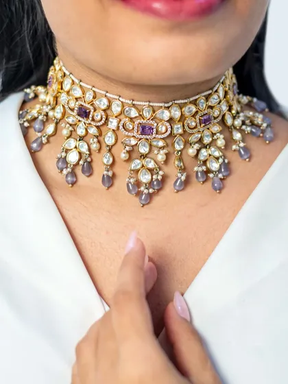 A close-up of a beautiful kundan choker with delicate purple stone drops. This piece combines traditional craftsmanship with a touch of modern color, making it versatile for various occasions.