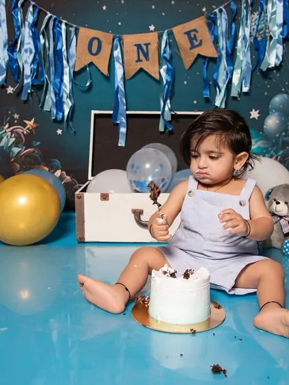 Exploring the textures and tastes of a birthday cake is a big adventure for a one-year-old. This shot captures his focus and determination during his fun and messy cake smash photoshoot.