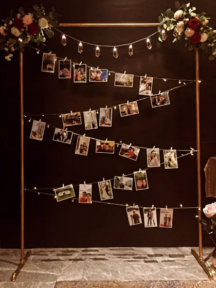 A wonderful way to display cherished memories. This custom photo stand with fairy lights and floral accents is a perfect, heartfelt addition to an anniversary or milestone birthday party.