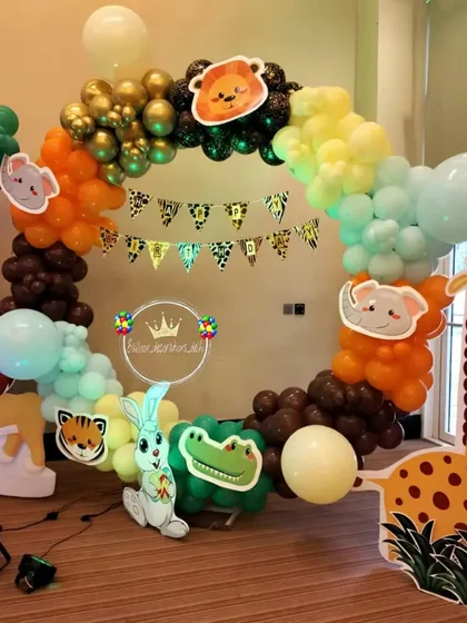 A circular balloon arch with a jungle animal theme, featuring various animal cutouts and a safari-print pennant banner.