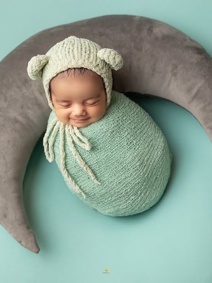 Another joyful smile from this little one, this time nestled in a crescent moon prop. The bear-ear bonnet adds an extra touch of cuteness to this dreamy setup.