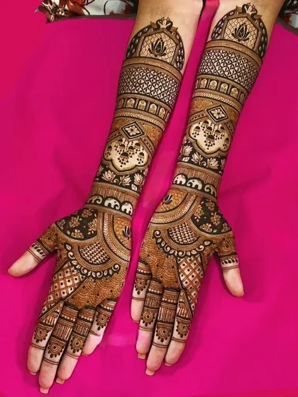 A perfect example of a full-coverage, symmetrical mehendi design. The fine lines, detailed jaal pattern, and lotus motifs create a stunning look that extends up to the elbows.