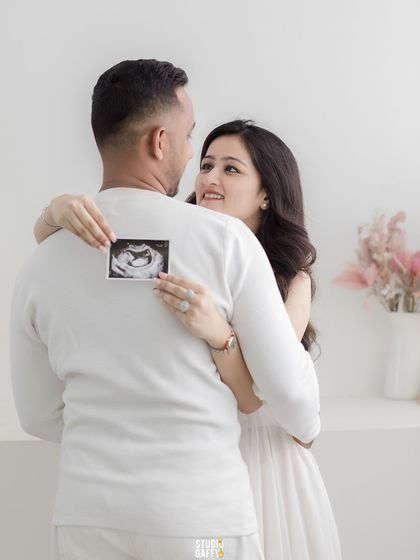 A creative announcement shot, with the mother-to-be holding the sonogram picture behind her partner's back.