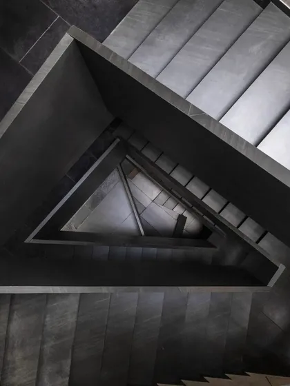 A detail from the Brick House, where the staircase is treated as a sculptural element. The interplay of black pigmented lime plaster, raw concrete, and natural light creates a dramatic, Escher-like geometry that evolves as you move through the space.