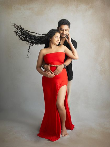 I love creating dynamic and romantic portraits like this one. The wind-swept hair adds a touch of motion and drama to this studio shot of a couple embracing, their hands forming a heart on the baby bump.