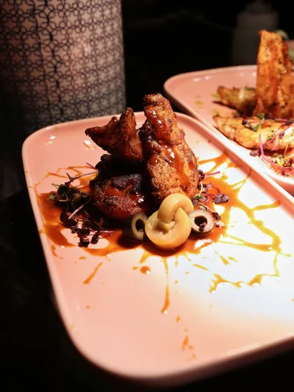 From our "Flames of the Orient" menu, this dish features succulent chicken with a rich, glossy sauce, artfully arranged with cashews and microgreens on a modern pink plate.