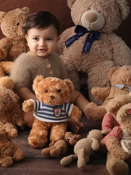 The king of the teddies. This portrait captures a sweet, interactive moment between the baby and his teddy bear friends. The warm brown tones make it feel extra cozy.