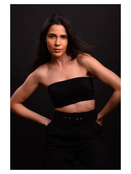 A minimalist and modern fashion portrait. The simple black outfit and dark background create a sleek and sophisticated look.