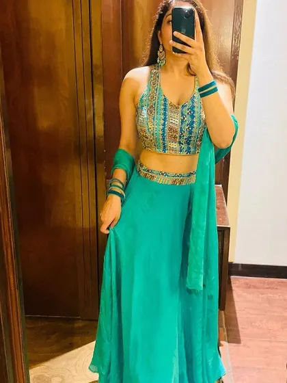 A mirror selfie showing off a lovely turquoise lehenga with a colorful embroidered blouse. A great rental choice for a beach wedding or a summer function.