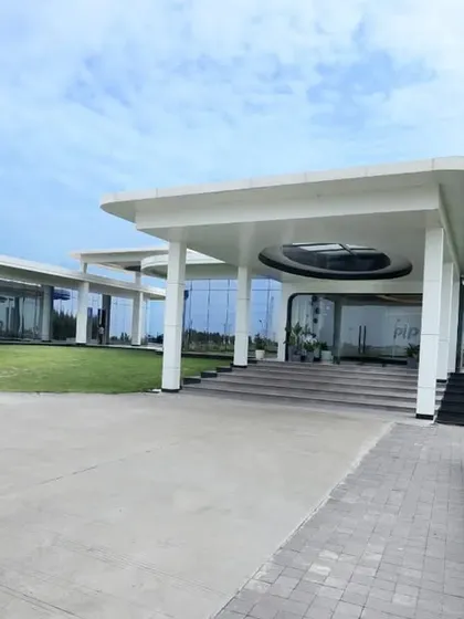 The exterior of a modern institutional building, defined by its expansive glass facades and a prominent, cantilevered entrance canopy. The design emphasizes transparency and a seamless connection with the surrounding landscape, reflecting a forward-thinking organization.
