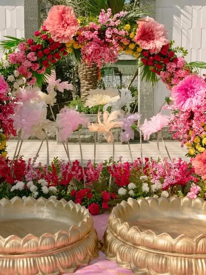 The Haldi ceremony spot, with two large brass urlis set before a beautiful arch of pink, yellow, and red flowers.