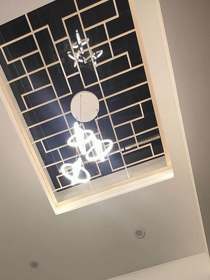 A close-up of a custom-designed skylight with a geometric grill and modern chandelier. This feature brings natural light into the home while also serving as a unique decorative element.