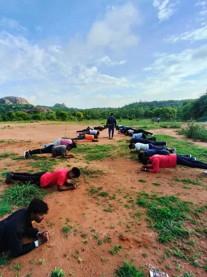 Core strength is key for climbing. Here, participants engage in a group plank exercise with the Ramanagara hills in the background.