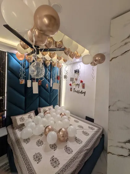 I specialize in creating personal and romantic birthday surprises right in your bedroom. This setup features elegant rose gold and white balloons on the ceiling, more balloons scattered on the bed, and a special wall display with your personal photos hanging from ribbons.
