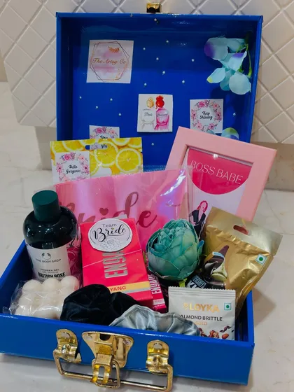 A peek inside our custom bridal hamper, packed in a reusable blue trunk. This one is filled with pamper essentials from The Body Shop, a "Boss Babe" frame, a "Team Bride" sash, and sweet treats to celebrate the bride-to-be.