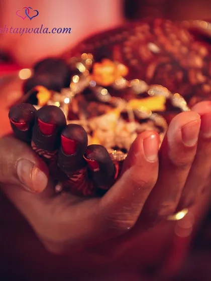A close-up of a bride's hands holding sacred offerings during a puja. These traditions are the heart of an Indian marriage.