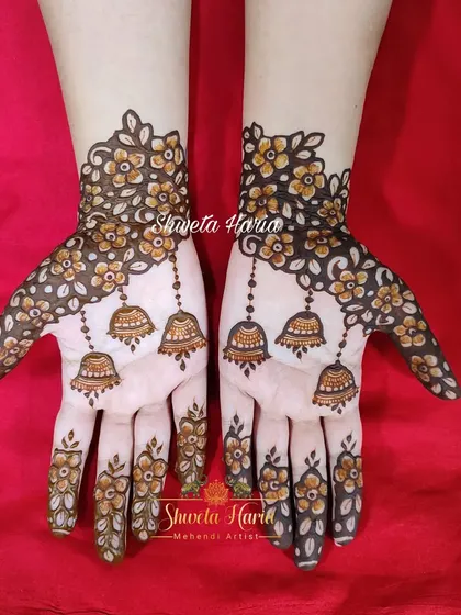 A fancy and playful henna design. This pattern features scattered floral motifs with delicate chains of hanging jhumkas (bells), creating a look that is both elegant and whimsical.