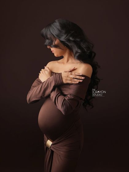 An artistic pose where her hair conceals her face, drawing all attention to her hands cradling her bump. This is a powerful, anonymous portrait of motherhood.