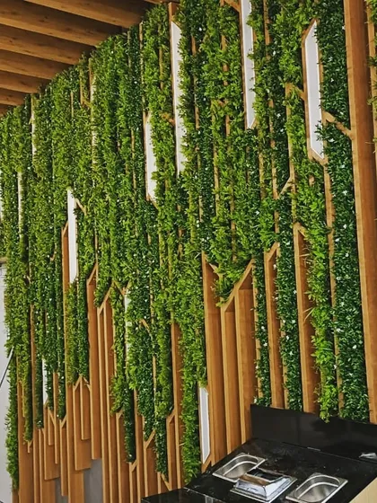 This is a unique artificial green wall I designed for a restaurant space. I integrated the greenery with custom-cut wooden panels to create a dynamic, textured look that complements the modern interior design.
