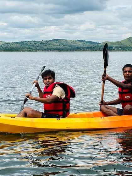 Two participants in a bright orange kayak paddle together, showcasing the vibrant equipment we use.