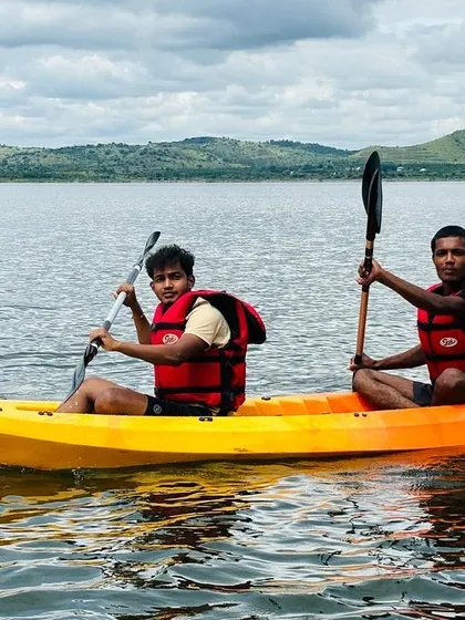 Two young men enjoying their time in a tandem kayak on the lake, all smiles during their adventure.