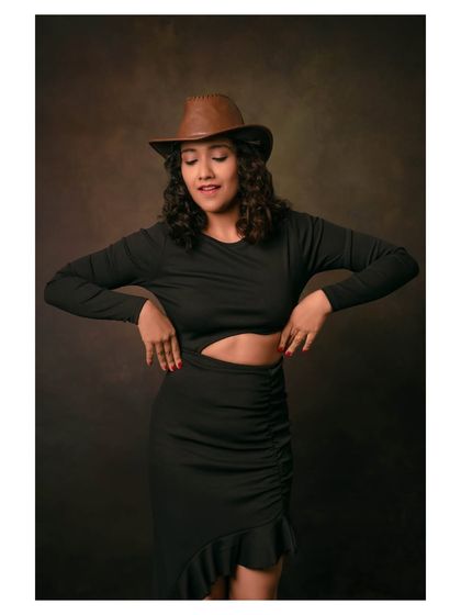 A joyful portrait of a model in a black dress and cowboy hat. Her expression is full of life and energy.