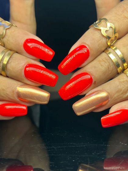 A powerful and contrasting manicure with bright red and metallic gold nails on a long, square shape.