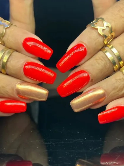 A powerful and contrasting manicure with bright red and metallic gold nails on a long, square shape.