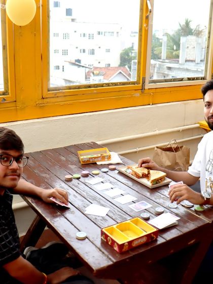 A game of 'Jaipur' being played over sandwiches. It's the perfect combination of a light meal and a light, fun game.