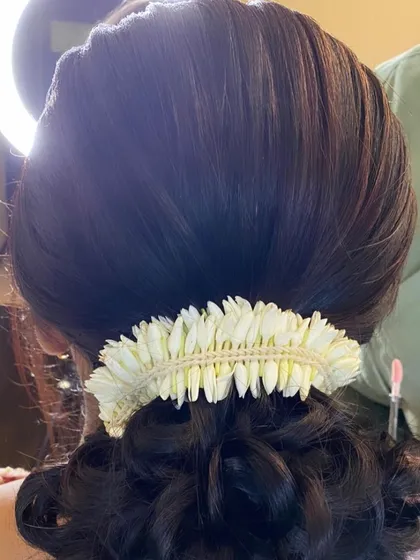 A detailed shot of the classic bridal bun, showing the smooth finish and the delicate jasmine flower accessory. This is a timeless and elegant look.