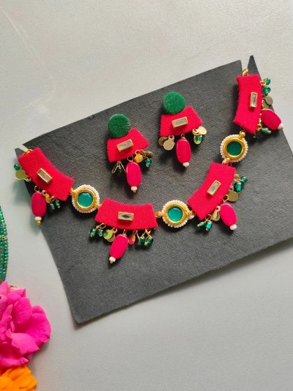 A vibrant red and green necklace set perfect for a Mehendi or Haldi ceremony. The design uses fabric pieces and beads to create a colorful, floral-inspired look.