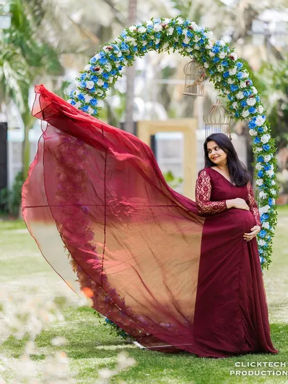A stunning solo portrait showcasing a flowing maternity gown against a circular floral arch. This image highlights how I use props and wardrobe to create elegant and impactful photographs.
