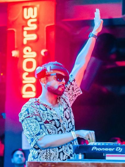 One hand up, commanding the stage at Sunburn Union. The red neon sign adds to the drama.